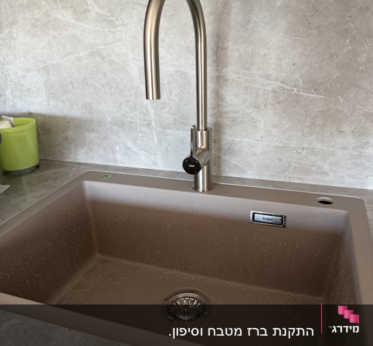 כיור מטבח עם ברז נירוסטה על רקע שיש